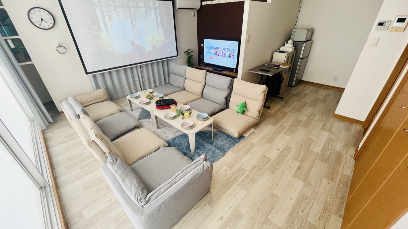 お気軽スペースAMAN2号店の明るい室内全景。フローリングにソファ席とテレビ