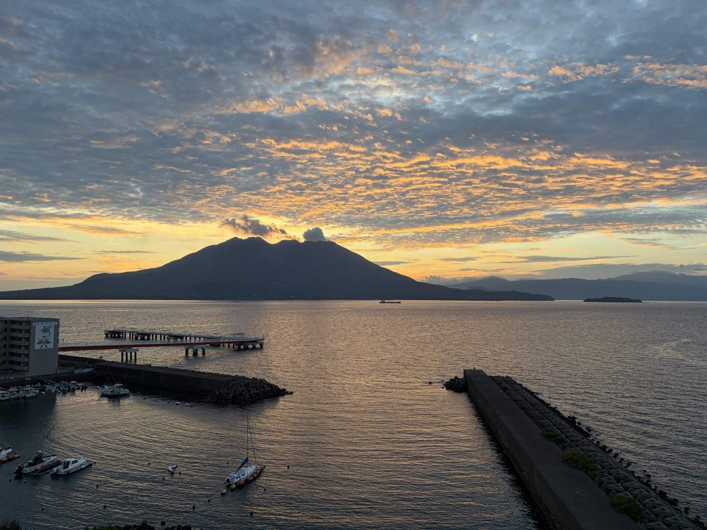 アートホテル鹿児島の客室から見た明け方の桜島。朝焼けの空と錦江湾、手前にヨットハーバー