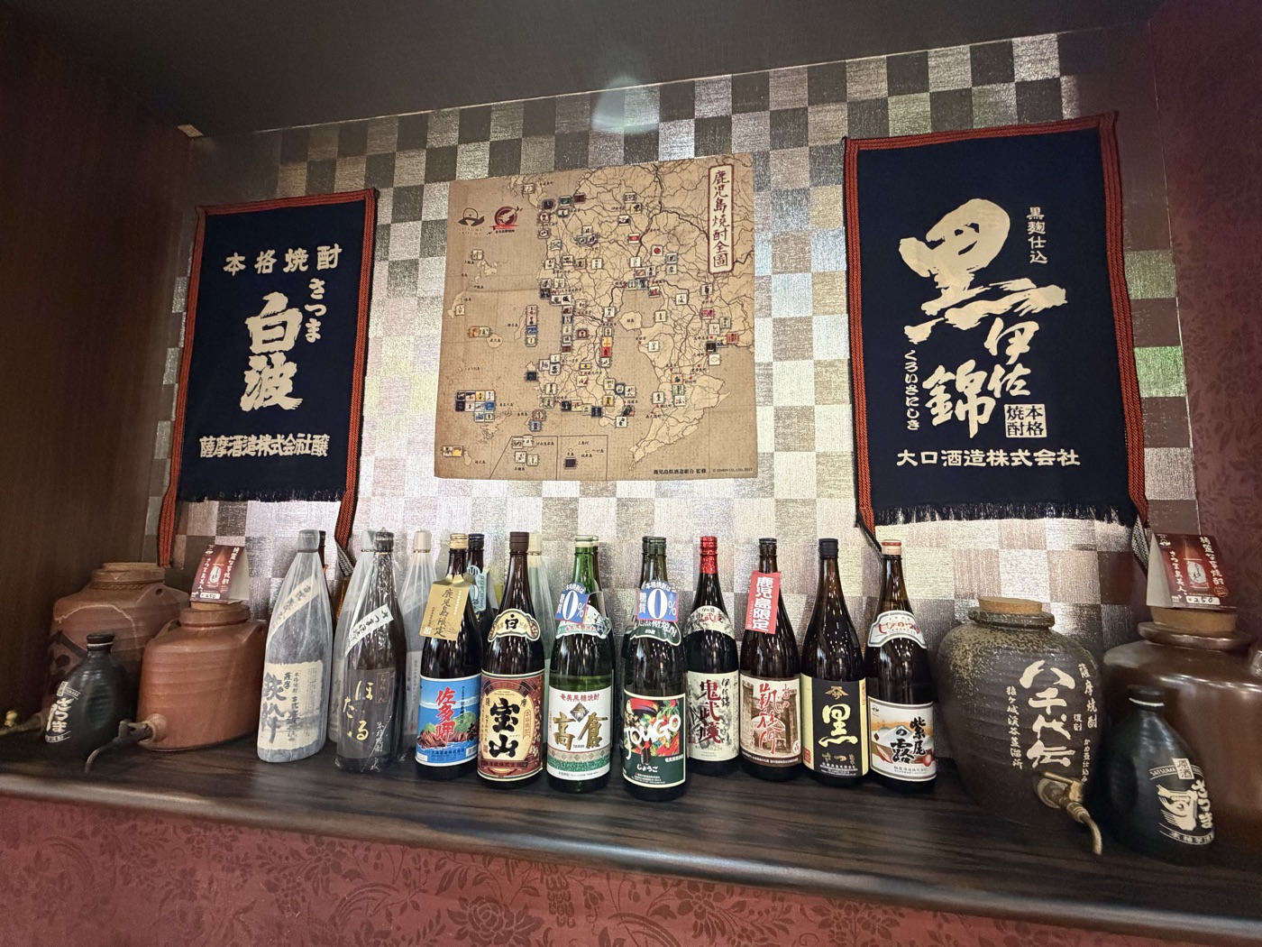 キリツ店内の焼酎棚。白波・黒伊佐錦の暖簾と鹿児島焼酎の一升瓶がずらり