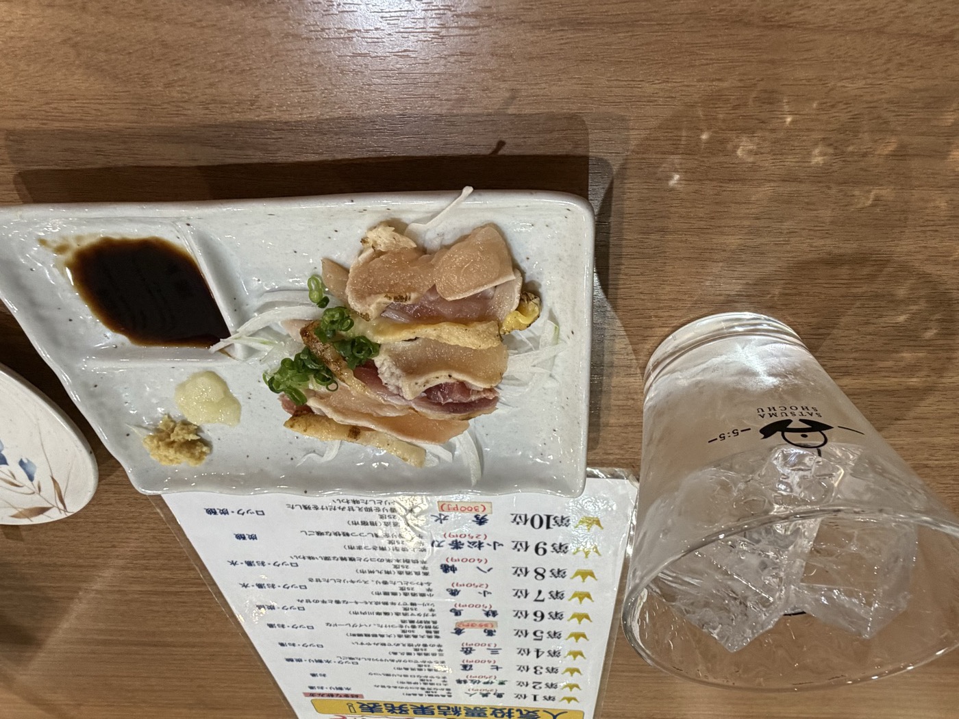 キリツのとり刺し350円と焼酎ロック。店内掲示の焼酎人気投票表と一緒に